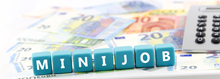 Schriftzug "Minijob" aus Würfeln auf Euroscheinen