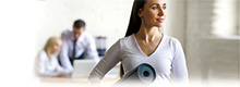 Frau im Büro mit Yogamatte unterm Arm