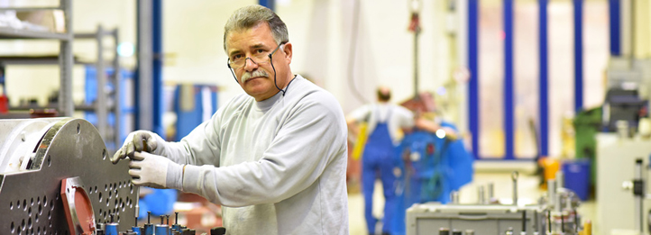 Älterer Arbeiter montiert Getriebe in einer Fabrik.