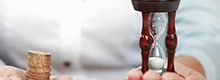 Hände mit Sanduhr und Geld