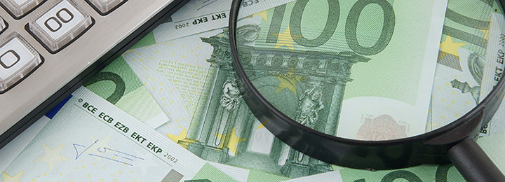 Geld mit Vergrößerungsglas und Taschenrechner