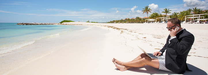 Geschäftsmann am Strand mit Laptop und Smartphone